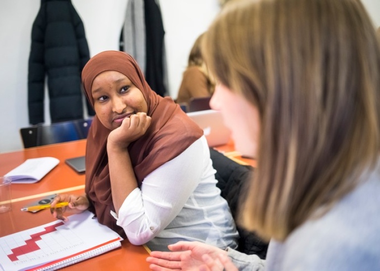Två kvinnliga studenter samtalar. Den ena bär hijab, den andra inte. Foto: Niklas Björling