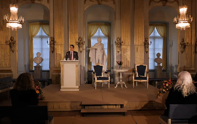 Börssalen, Svenska Akademien, Tomas Riad håller tal och några personer i publiken syns bakifrån