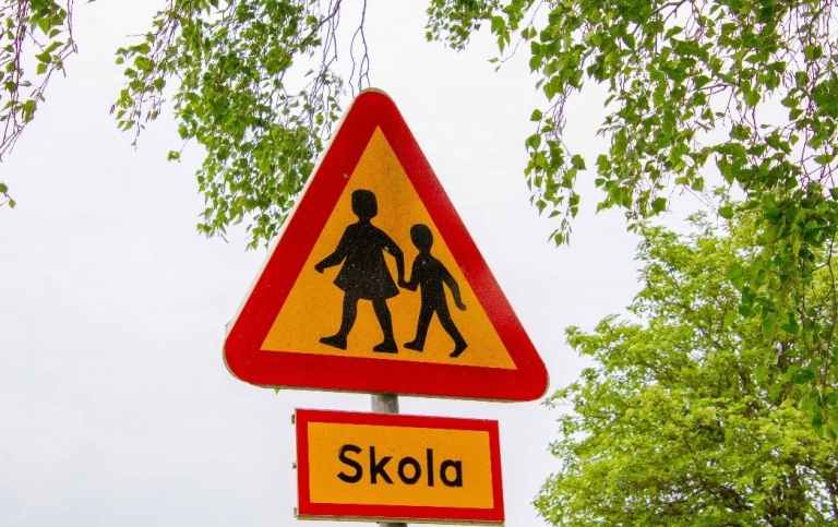 Traffic sign warning triangle with two children, below a sign saying 