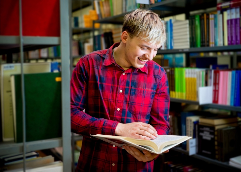 Young male researcher studying a book in an archive room. 