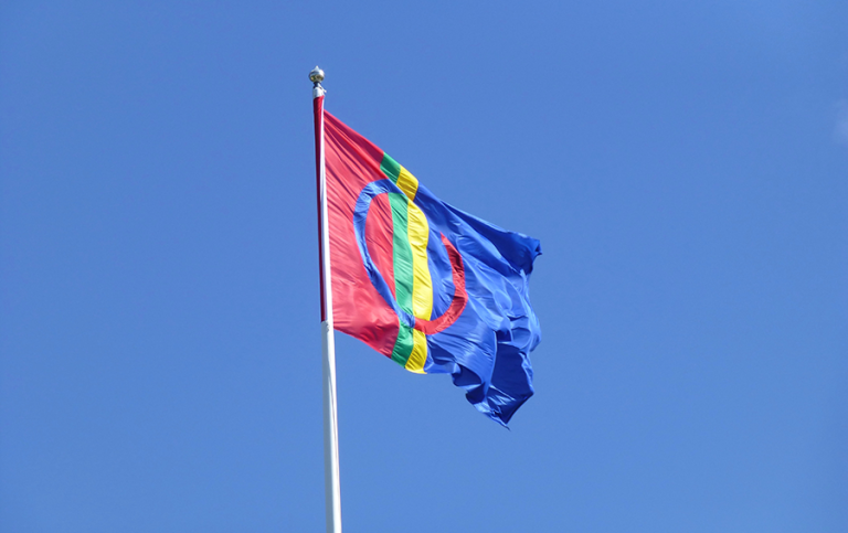 Saemien saevege - Samiska flaggan på flaggstång mot blå himmel