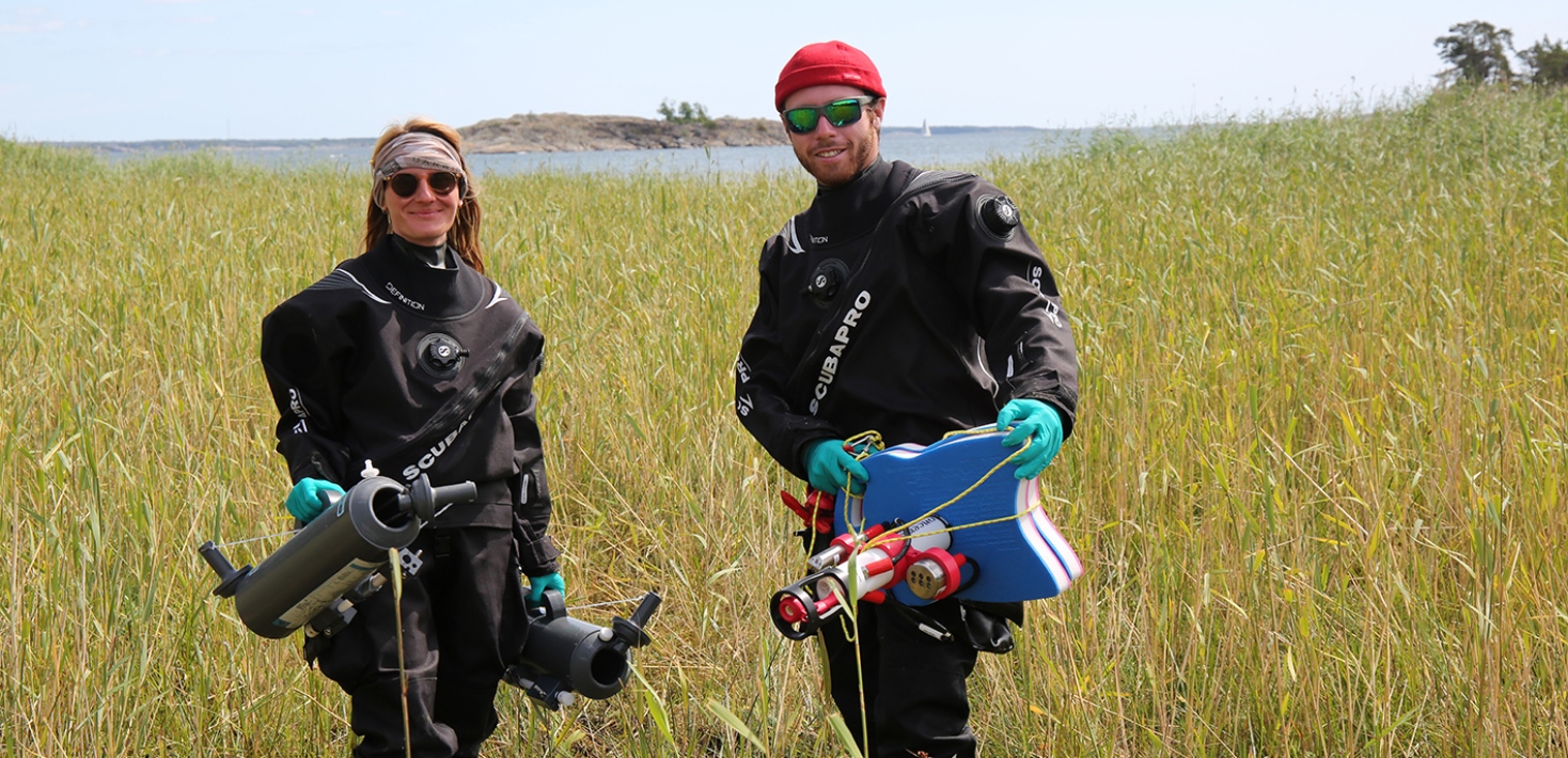 Two team members with sampling equipment in a shallow bay at Askö.