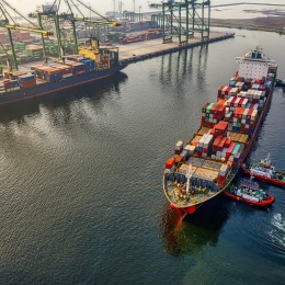 Flygfoto över fraktfartyg lastade med containrar i en hamn.