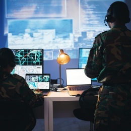 Two people in a military control room with technical devices.