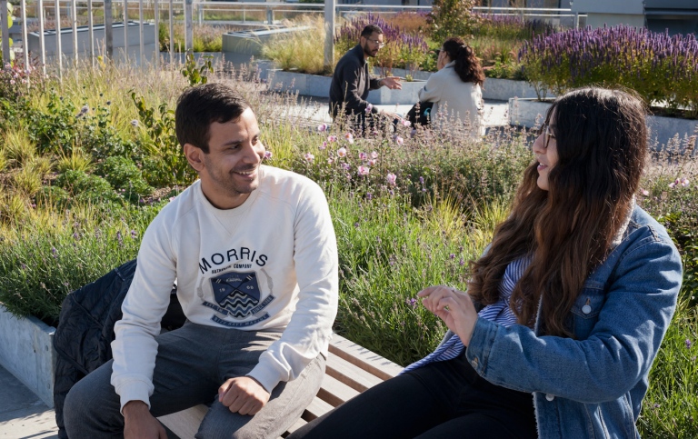 Manlig och kvinnlig student samtalar på terrass på Campus Albano. 