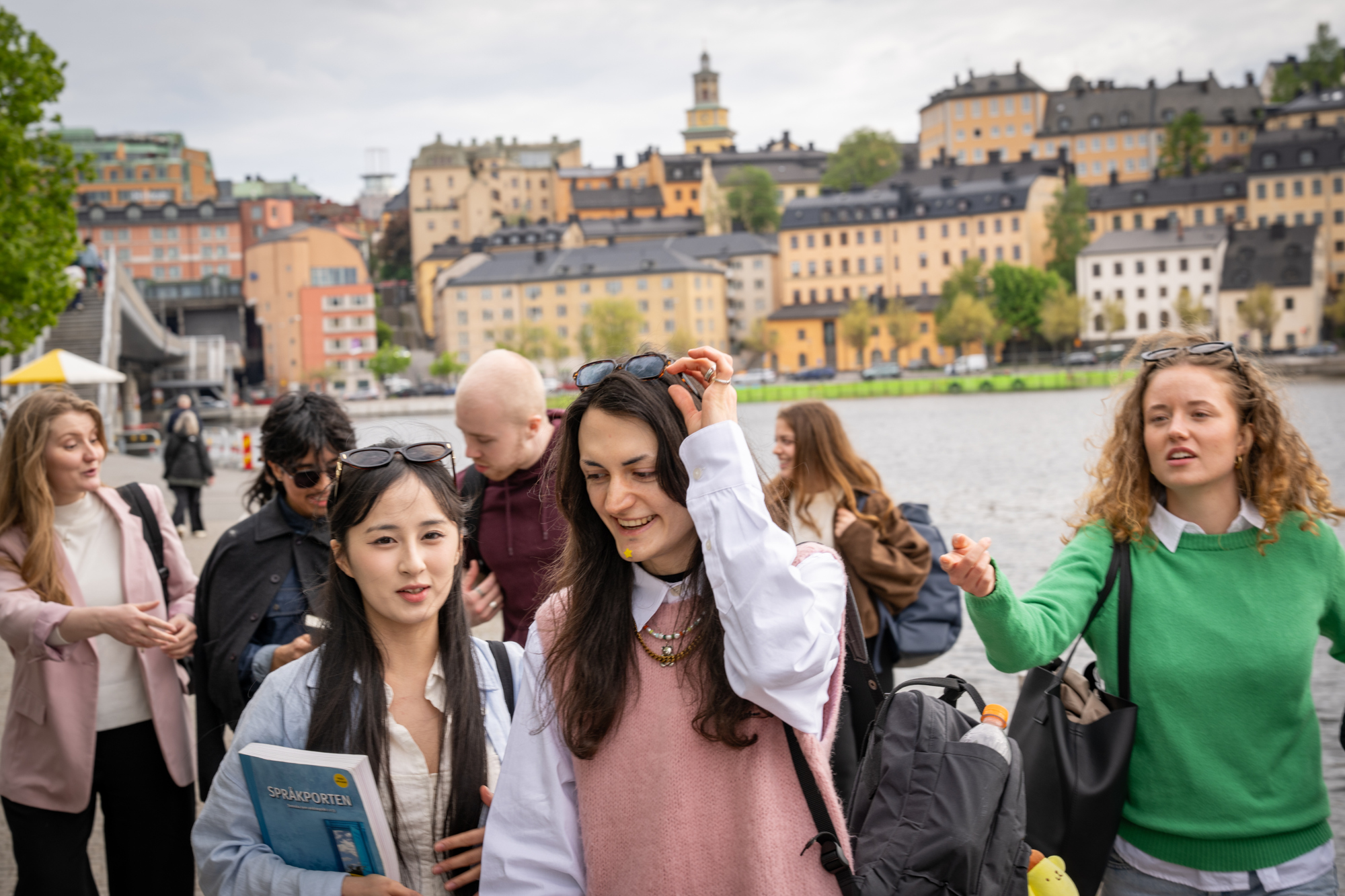 Studenter i stan med vatten och byggnader i bakgrunden.