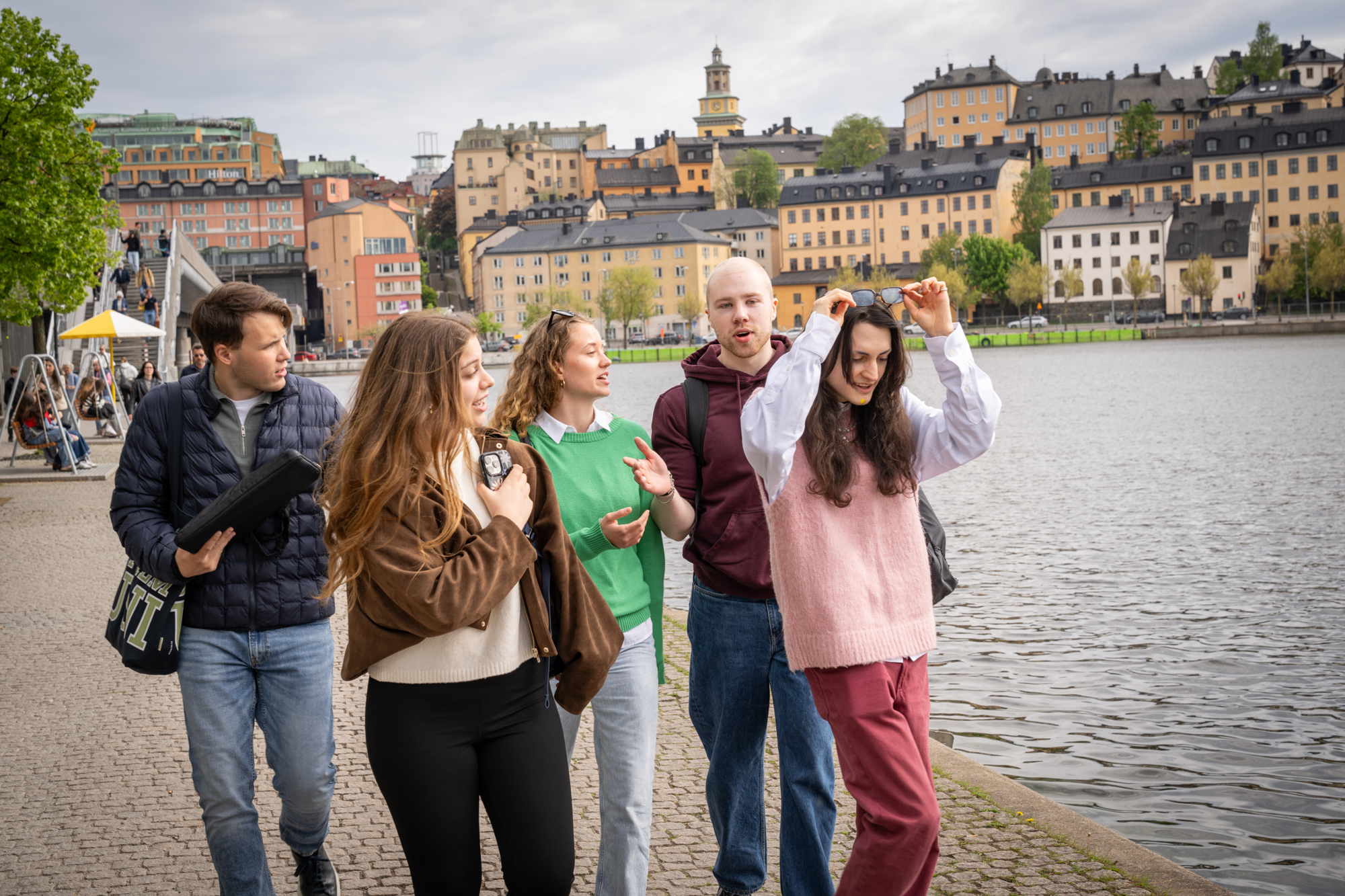 Studenter i stan med vatten och byggnader i bakgrunden.