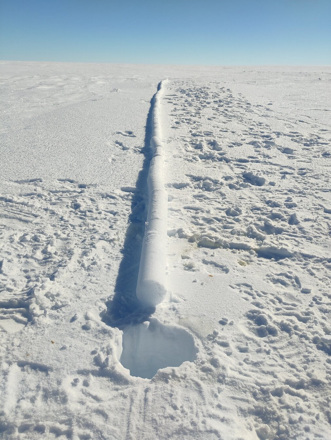 a drilled ice core hole stretching off into the distance.