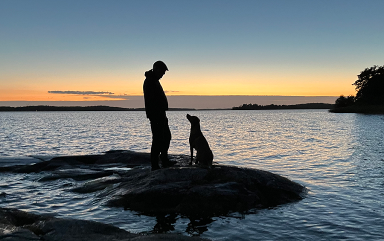 Silhouette of Man and dog in front of a lake