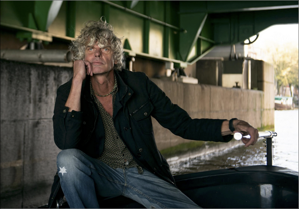 man sitting on small boat under a bridge
