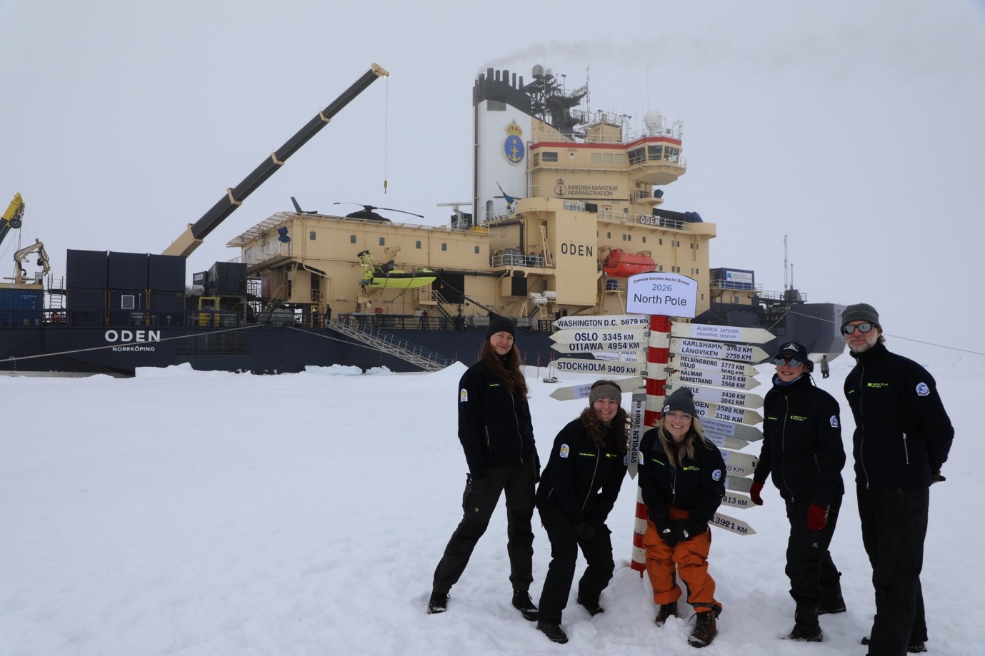 Caption: The meteorology and aerosol team on the ice, with the traditional North Pole pole indicating the distance to the participants' hometowns (from the left: Linnea Huusko and Irene Bellagente (Stockholm University), Missy Westland (University of British Columbia), Faustine Mascaut (Chalmers University of Technology), and Matthew Shupe (University of Colorado, NOAA, and Stockholm University).