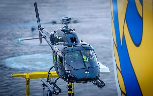 Helikopter landar på däck, virvel i vattnet bakom.