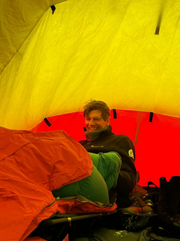 Image of Bram smiling while sitting in a tent in Antarctica.