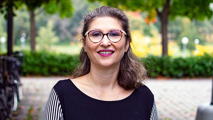 Eleonora Mussino standing outside on campus, greens and parked bicycles in the background.