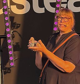 Jenny Larsson håller i en en liten hjulförsedd leksakshäst i trä.
