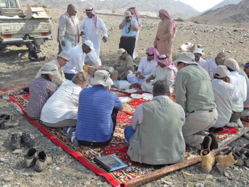People sitting on a matt having lunch in Arabian desert.
