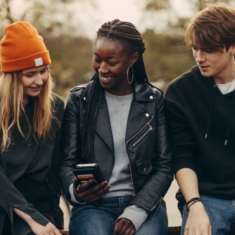 Tre  studenter tittar på en mobil. Foto: Viktor Gårdsäter