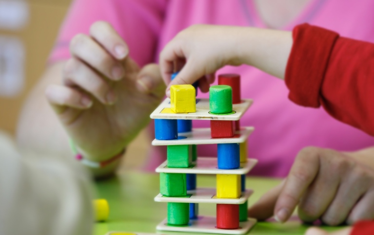 Children constructing a tower with small blocks and plates.