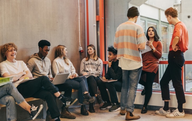 Studenter som sitter och pratar i en korridor.