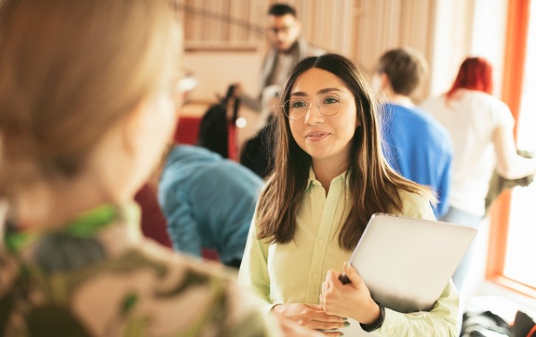 Två studenter samtalar i en föreläsningssal.