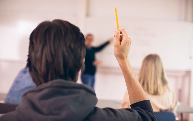 Student räcker upp handen på en föreläsning.