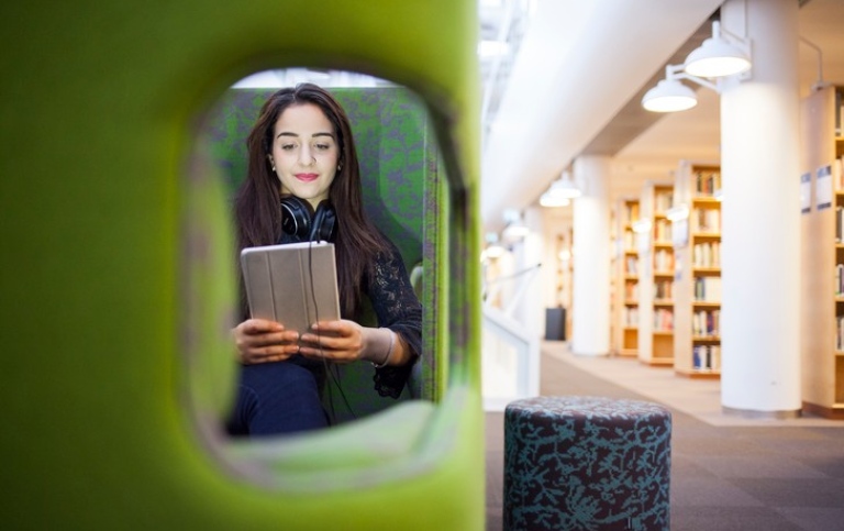 Kvinnlig student i grön stol på Biblioteket. Foto: Niklas Björling
