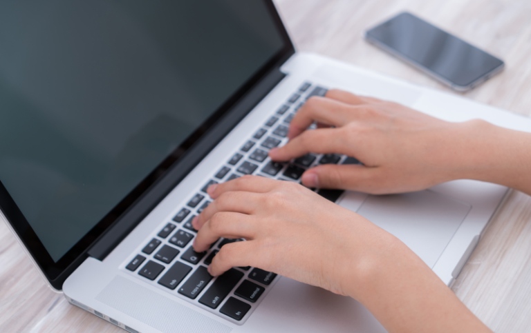 Woman typing on laptop.