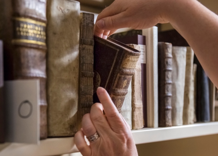 Hand som tar ner böcker från en bokhylla