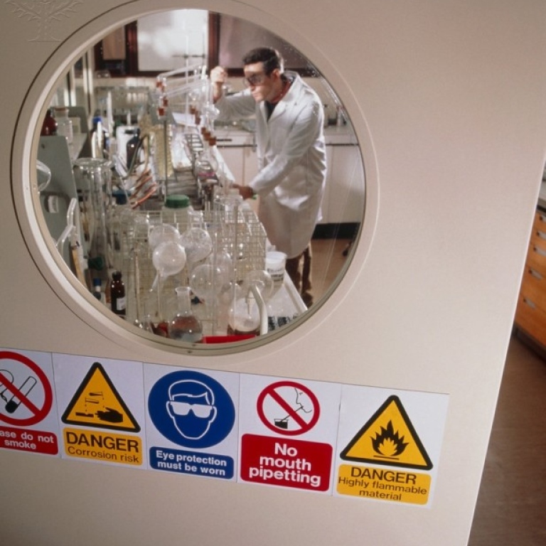 Dörr, med fem varningsskyltar, in till ett laboratorium. Foto: Tek image/Science photo Library.