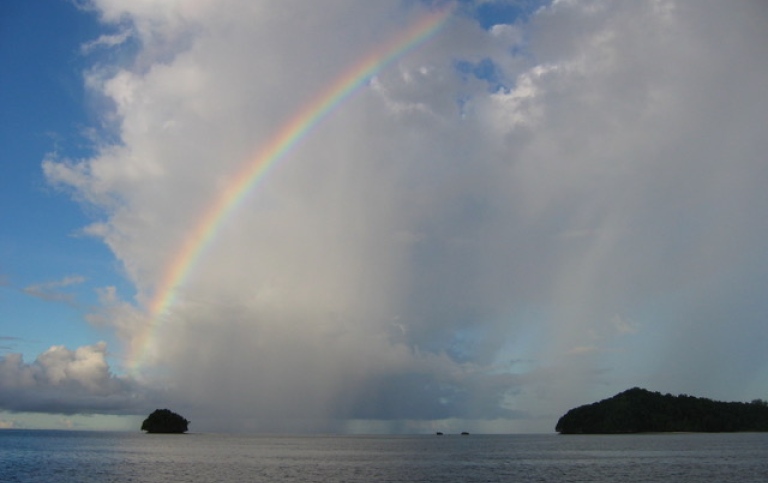 cloudy sky with a rainbow and two islands on the horizont