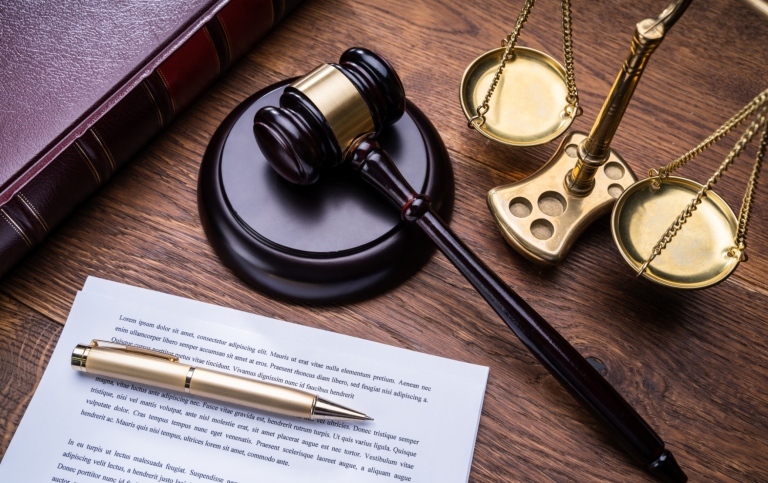 Wooden Gavel Golden Scale And Law Book On Table