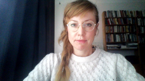 Bild på Karin Ahlberg i vit kofta och glasögon