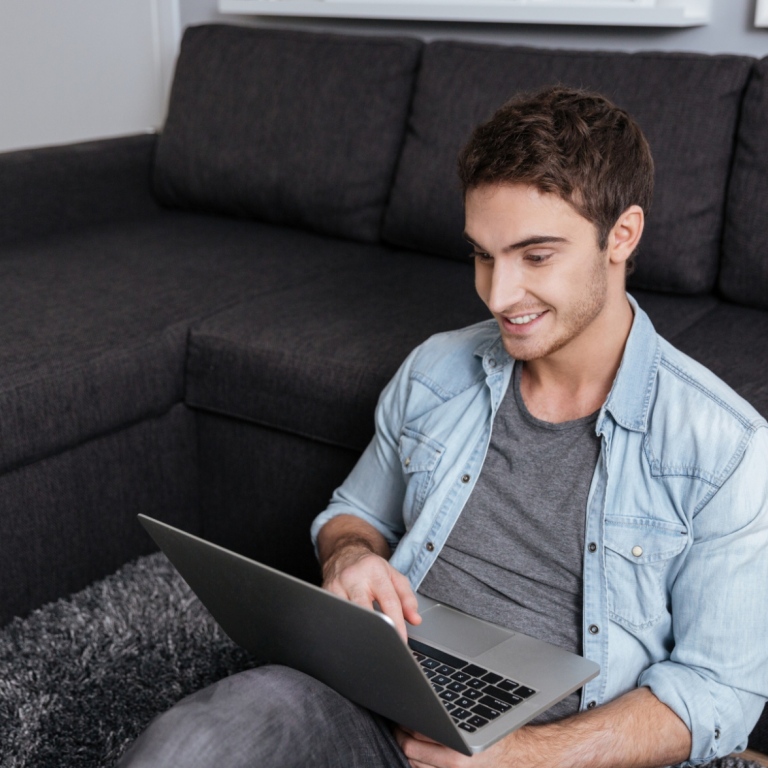 Glad kille med laptop i hemmamiljö. Foto: Mostphotos