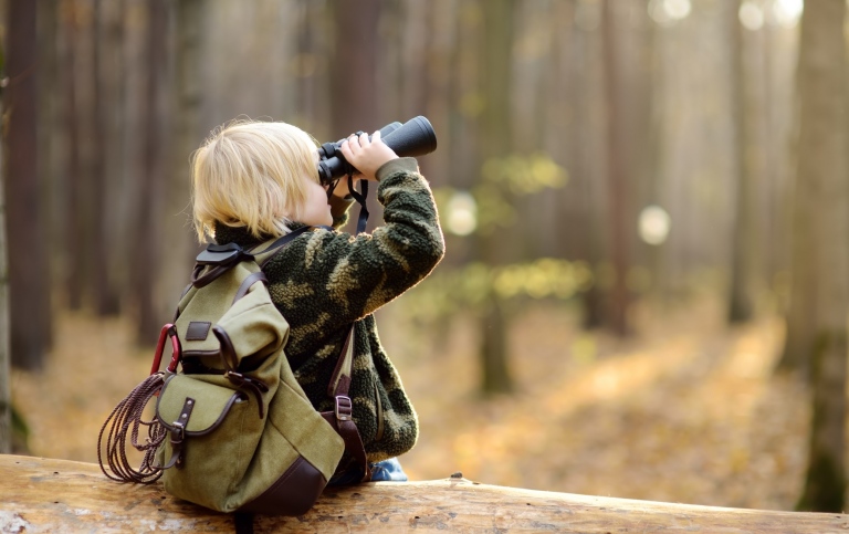 Pojke med kikare i skogen