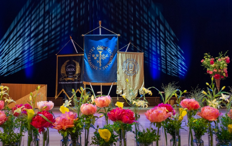 Aula magnas scen med blommor i förgrunden.