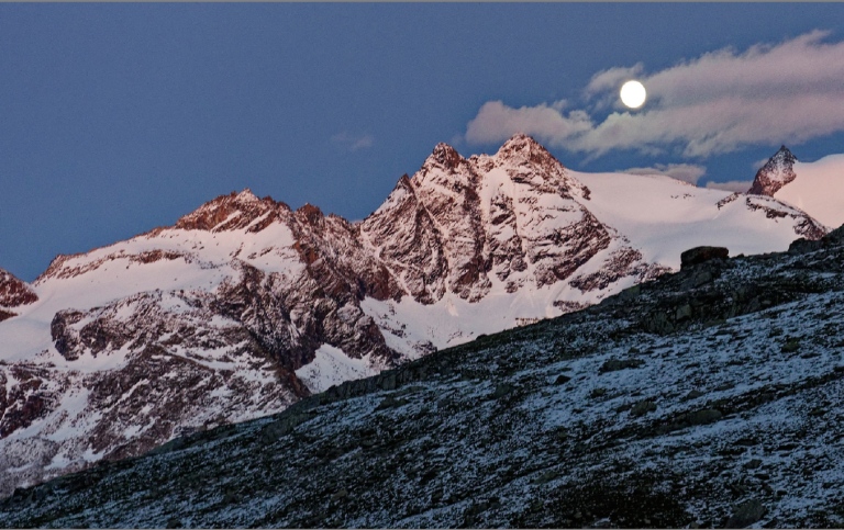 mountain range at dusk with a nice full moon to the right of the frame