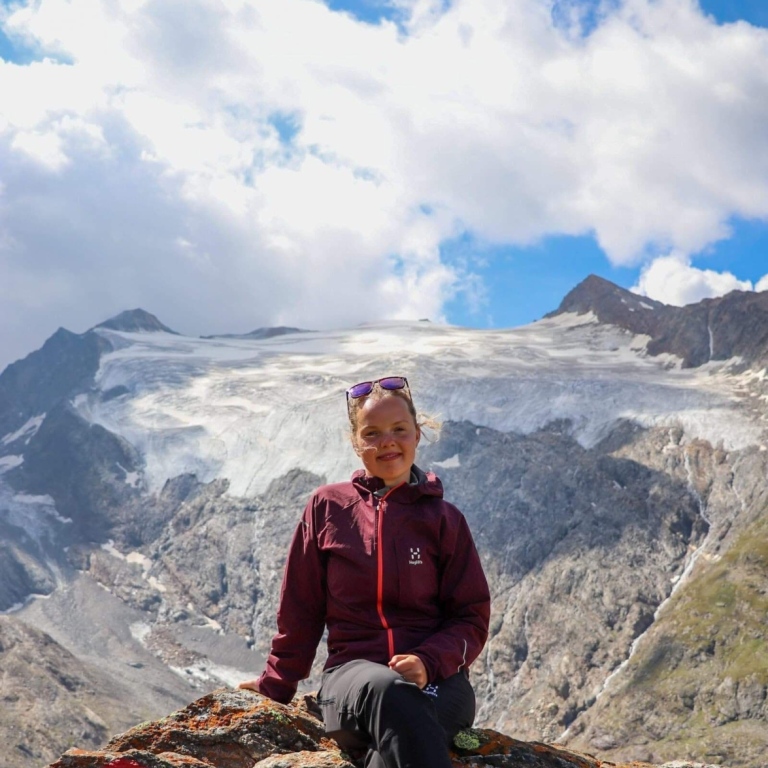 Mikaela sitting on a rock on a mountain somewhere i Cyprus witha glacier in the background