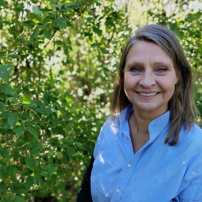 Helena Ahlsten porträtt ute framför gröna växter