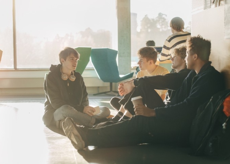 Students sitting on the floor in a group talking.