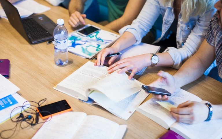 Studenter vid ett bord med studiematerial. Foto: Niklas Björling.