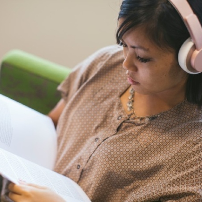 Rättigheter och skyldigheter - kvinna med hörlurar läser i ett häfte