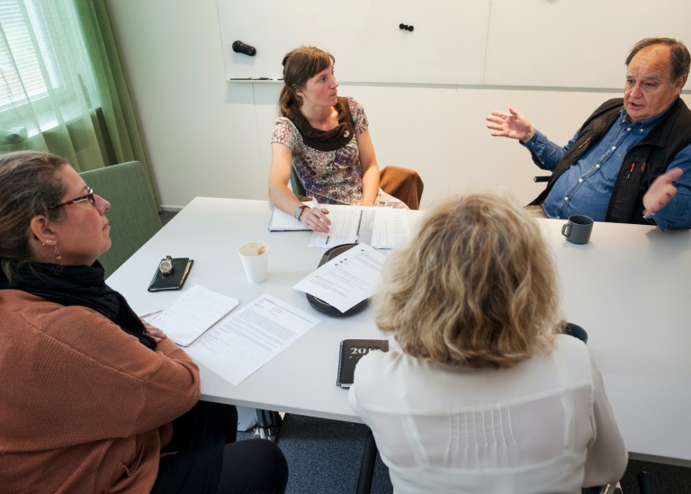 Medarbetare som sitter och diskuterar vid ett bord.