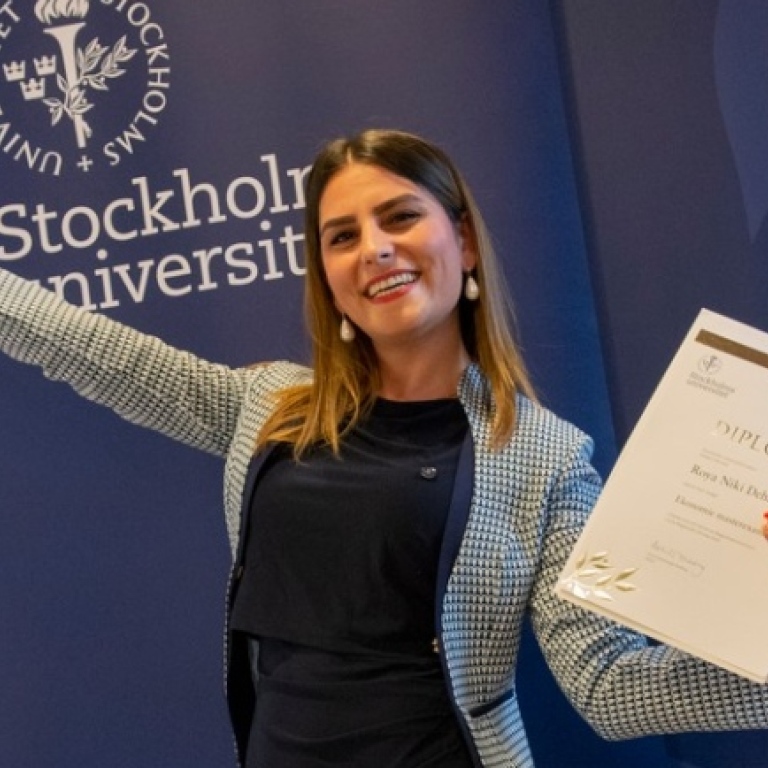 Glad magister med diplom i handen.