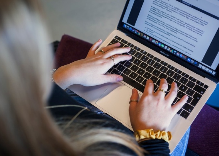 Student writing on laptop