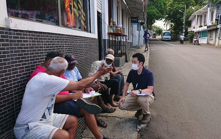 Koji talking to locals in a street on Mauritius