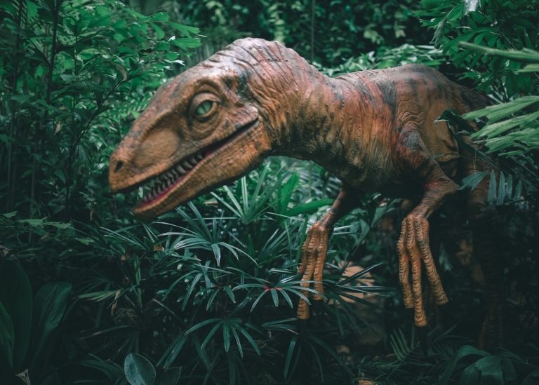 En dinosaurie tittar fram i djungeln.