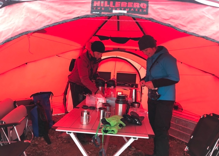2 people inside tent, set up table for dinner