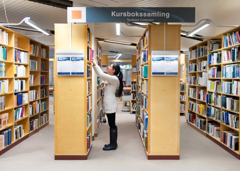 Student letar efter bok i kurslitteraturhylla