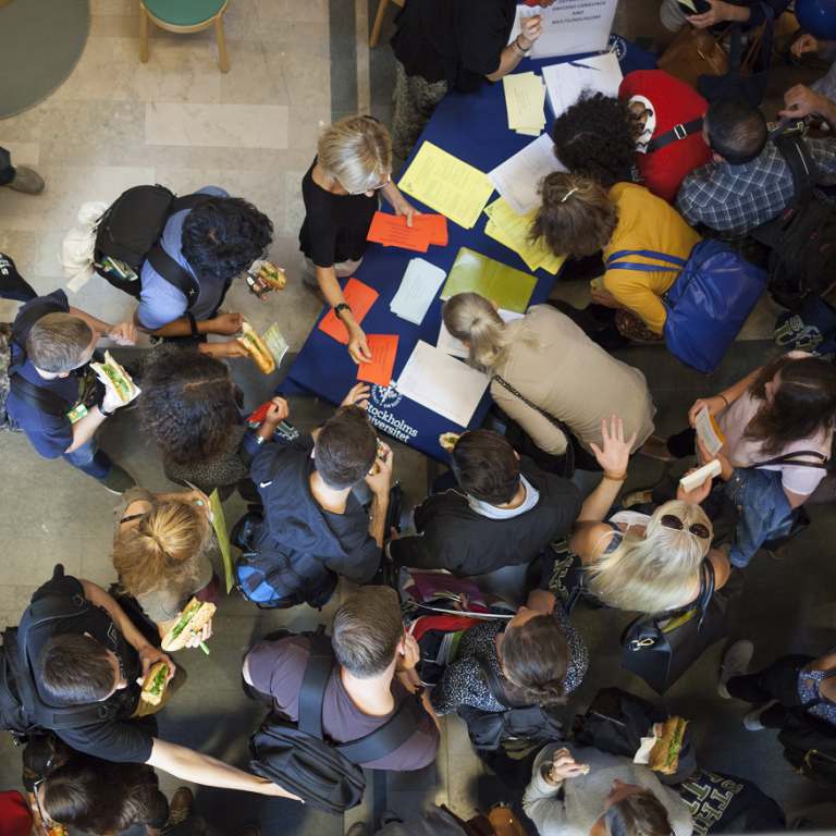 Many students seen from above, around a table with papers and brochures.