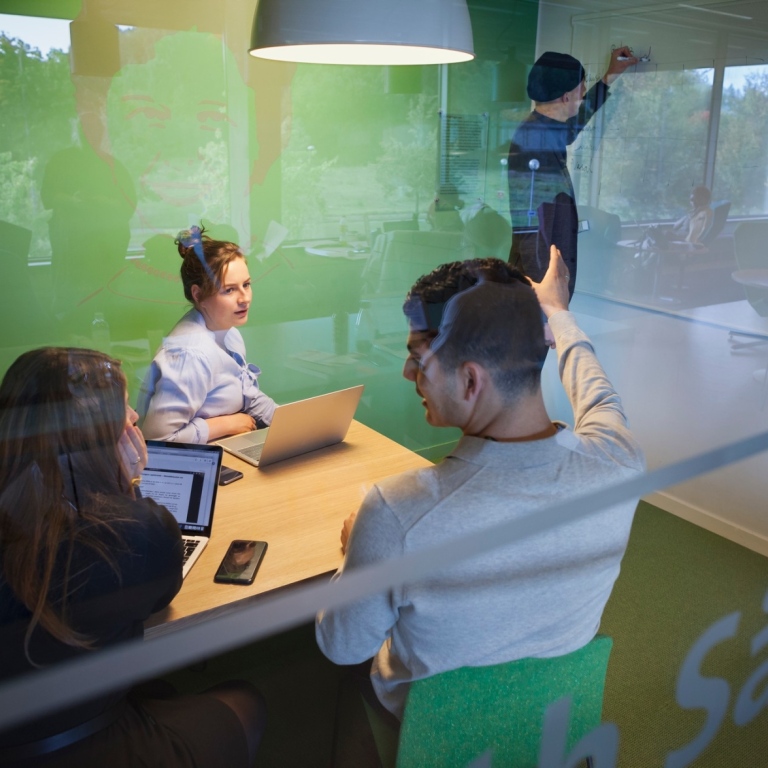 Studenter i grönt grupprum med glasvägg. Foto: Jens Olof Lasthein